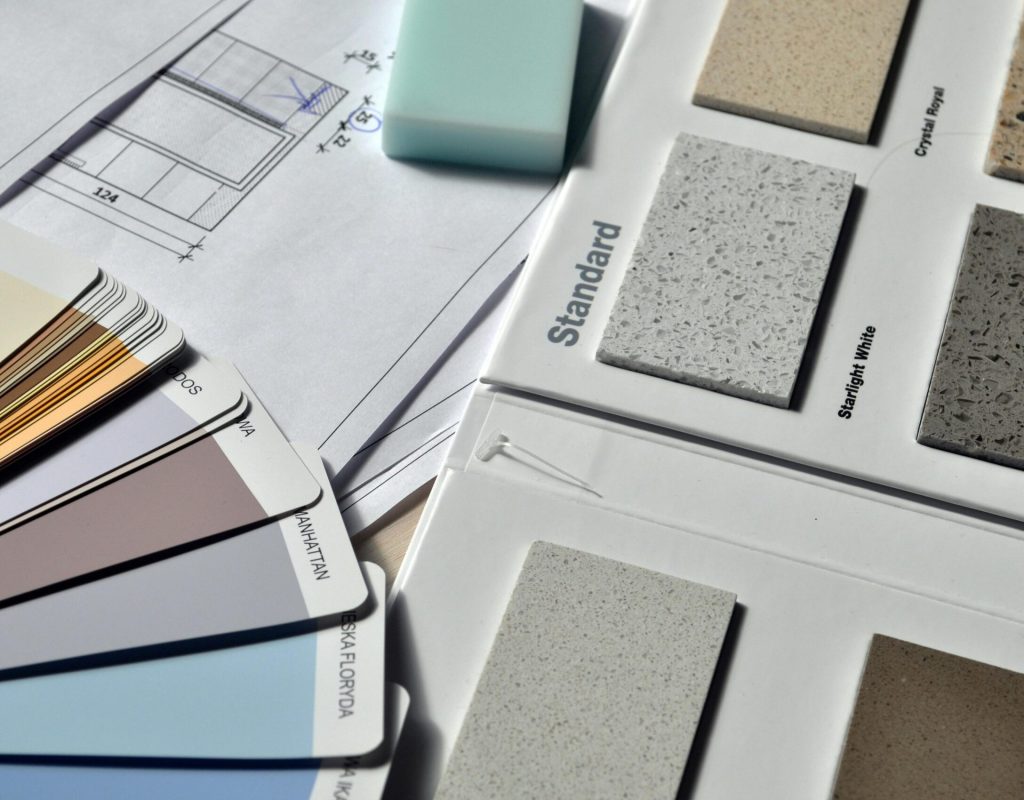 Color palette and material samples for interior renovation projects on a blueprint.